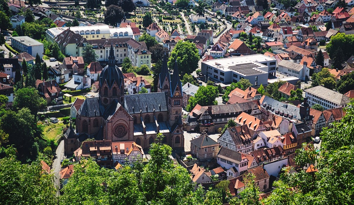 Blick über die Dächer der Heppenheimer Altstadt mit der Kirche St. Peter, umgeben von Grün.